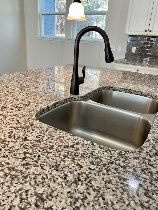 details with white cabinetry, stone countertops, decorative backsplash, and sink