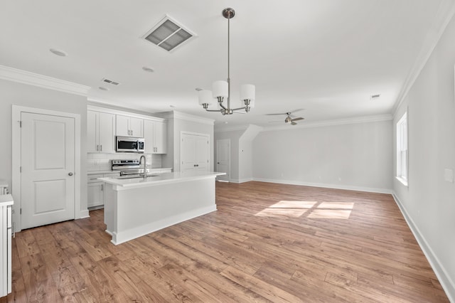 kitchen with white cabinets, appliances with stainless steel finishes, light hardwood / wood-style flooring, and decorative light fixtures