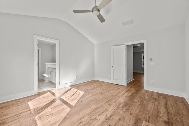 unfurnished bedroom with ceiling fan, light hardwood / wood-style floors, ensuite bathroom, a fireplace, and vaulted ceiling