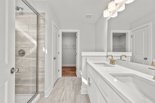 bathroom with walk in shower, vanity, and toilet