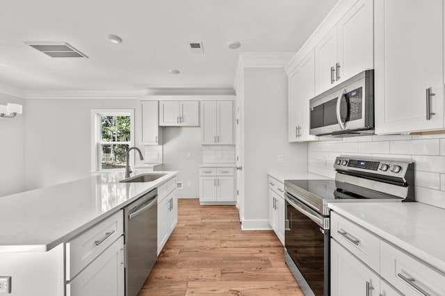 kitchen with stainless steel appliances, light wood-type flooring, sink, and white cabinetry