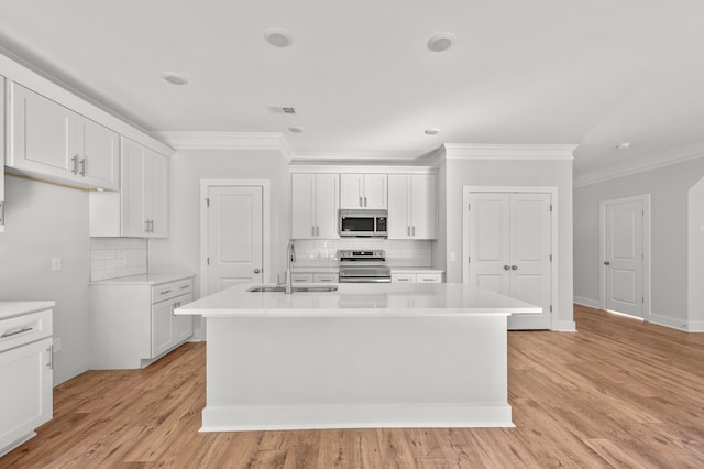 kitchen featuring appliances with stainless steel finishes, a center island with sink, and white cabinetry