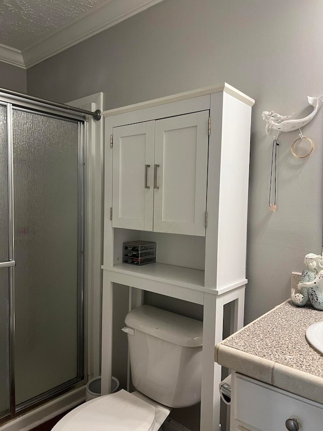 bathroom featuring toilet, ornamental molding, vanity, a textured ceiling, and walk in shower