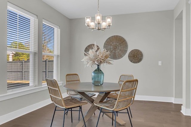 dining room with dark hardwood / wood-style flooring and an inviting chandelier