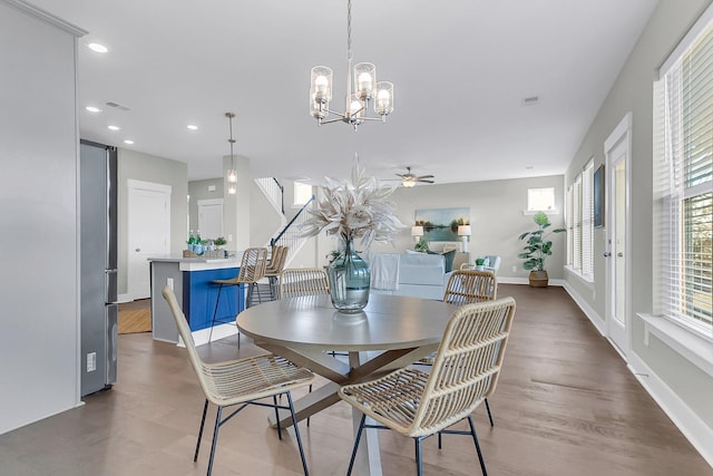 dining space with ceiling fan with notable chandelier and hardwood / wood-style flooring