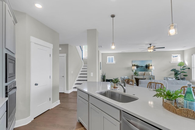 kitchen featuring appliances with stainless steel finishes, ceiling fan, sink, decorative light fixtures, and dark hardwood / wood-style floors