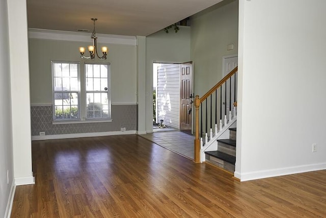 foyer featuring dark hardwood / wood-style flooring, an inviting chandelier, and crown molding