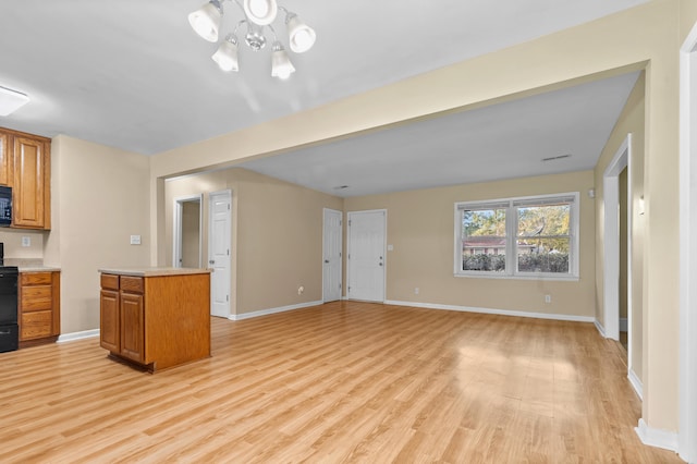 kitchen with black appliances, a kitchen island, light wood-type flooring, and an inviting chandelier