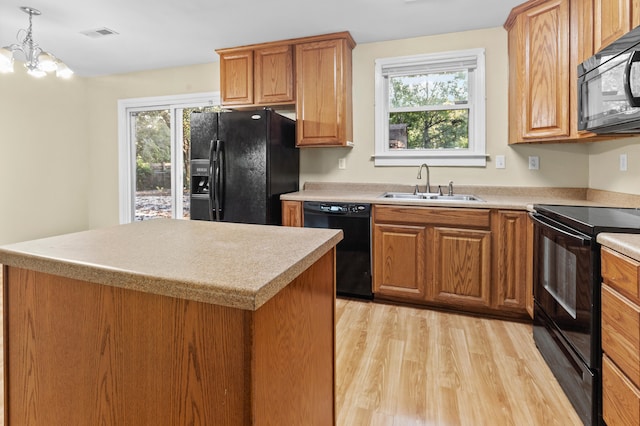 kitchen with light wood-type flooring, plenty of natural light, black appliances, and sink