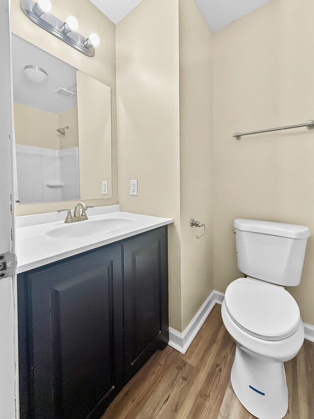 bathroom with walk in shower, hardwood / wood-style floors, vanity, and toilet