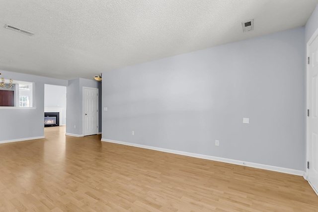 230 Darcy Ave, Goose Creek, SC 29445 - unfurnished living room with light wood-type flooring, baseboards, a glass covered fireplace, a textured ceiling, and a chandelier