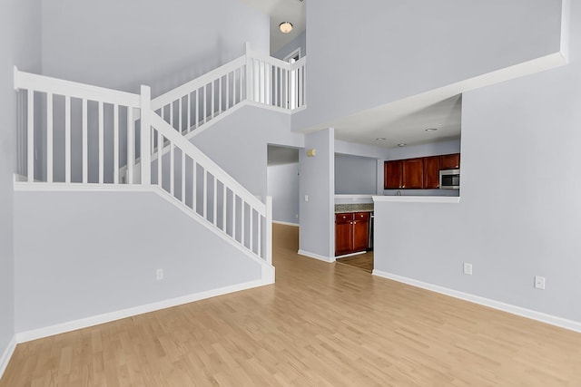 230 Darcy Ave, Goose Creek, SC 29445 - unfurnished living room featuring light wood finished floors, stairs, baseboards, and a high ceiling