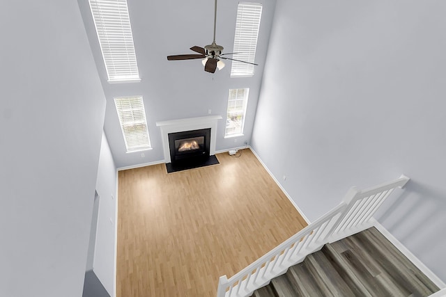 230 Darcy Ave, Goose Creek, SC 29445 - unfurnished living room featuring wood finished floors, baseboards, a high ceiling, ceiling fan, and a fireplace with flush hearth