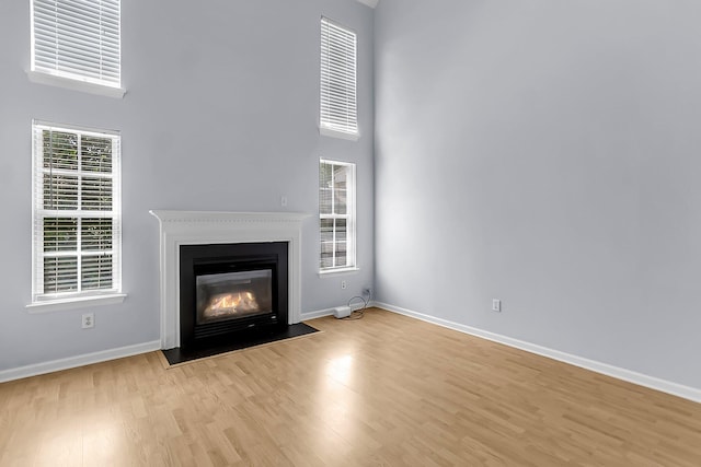 230 Darcy Ave, Goose Creek, SC 29445 - unfurnished living room featuring a high ceiling, light wood finished floors, a fireplace with flush hearth, and baseboards
