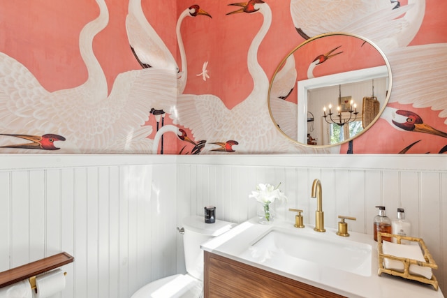 bathroom featuring vanity, an inviting chandelier, and toilet