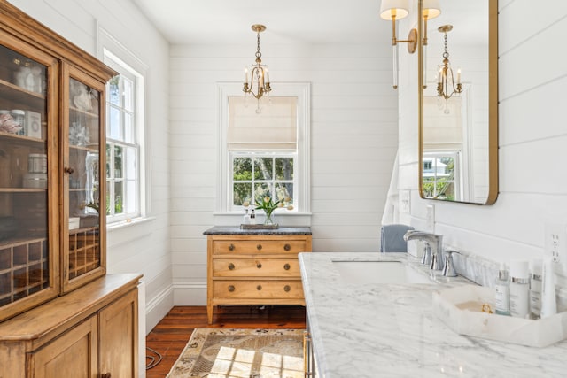 interior space featuring vanity, hardwood / wood-style flooring, wooden walls, and a wealth of natural light