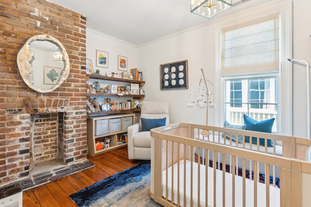 bedroom with a nursery area, hardwood / wood-style floors, and crown molding