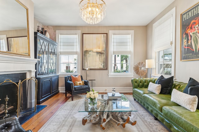 living room featuring light hardwood / wood-style flooring, a wealth of natural light, a notable chandelier, and a fireplace