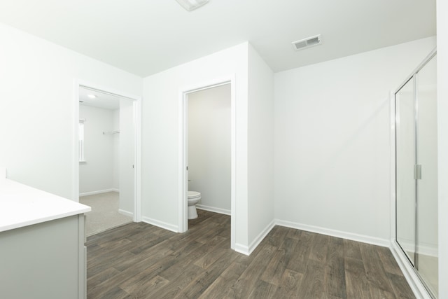 interior space with toilet, an enclosed shower, hardwood / wood-style floors, and vanity