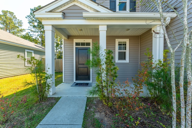 entrance to property with covered porch and a lawn