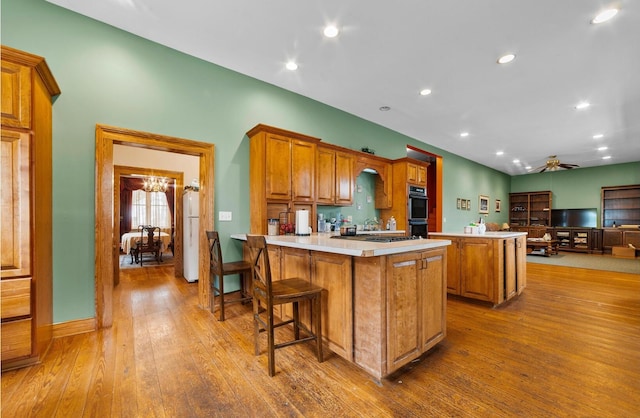 kitchen featuring double oven, a kitchen breakfast bar, a kitchen island, kitchen peninsula, and white fridge