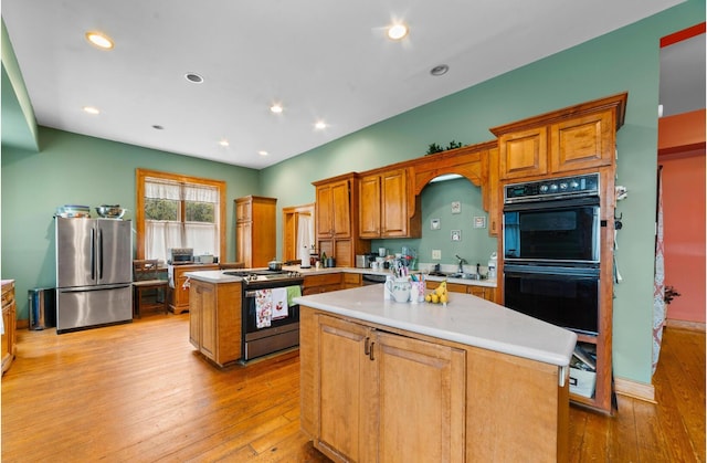 kitchen featuring appliances with stainless steel finishes, a center island, sink, and light hardwood / wood-style flooring