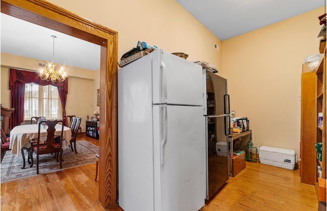 kitchen featuring white refrigerator, light hardwood / wood-style floors, hanging light fixtures, and a notable chandelier