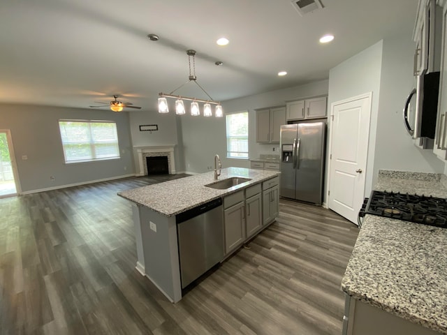 kitchen featuring a healthy amount of sunlight, appliances with stainless steel finishes, sink, and an island with sink