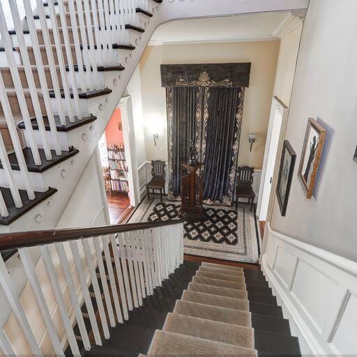 81 Rutledge Ave, Charleston, SC 29401 - staircase featuring wood finished floors, wainscoting, crown molding, and a decorative wall