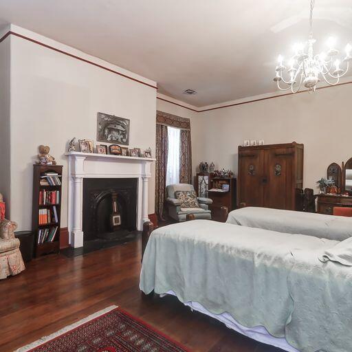 81 Rutledge Ave, Charleston, SC 29401 - bedroom with wood finished floors, a chandelier, ornamental molding, and a fireplace with flush hearth