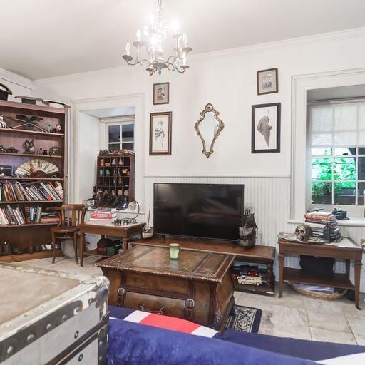 81 Rutledge Ave, Charleston, SC 29401 - living room featuring crown molding, a wainscoted wall, and a chandelier