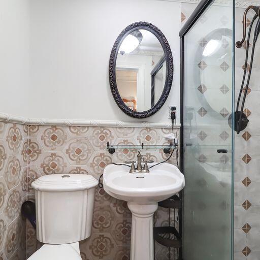 81 Rutledge Ave, Charleston, SC 29401 - bathroom featuring a stall shower, toilet, a sink, and wainscoting