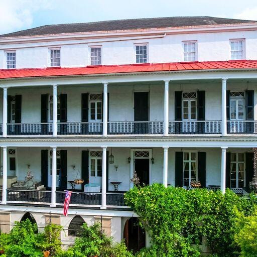 81 Rutledge Ave, Charleston, SC 29401 - view of front of house with stucco siding, a balcony, metal roof, and a standing seam roof