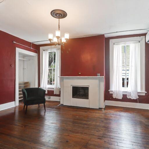 81 Rutledge Ave, Charleston, SC 29401 - living area featuring dark wood-style floors, a chandelier, baseboards, and a glass covered fireplace