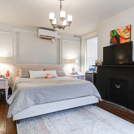 81 Rutledge Ave, Charleston, SC 29401 - bedroom featuring a wall mounted AC, wood finished floors, and a chandelier