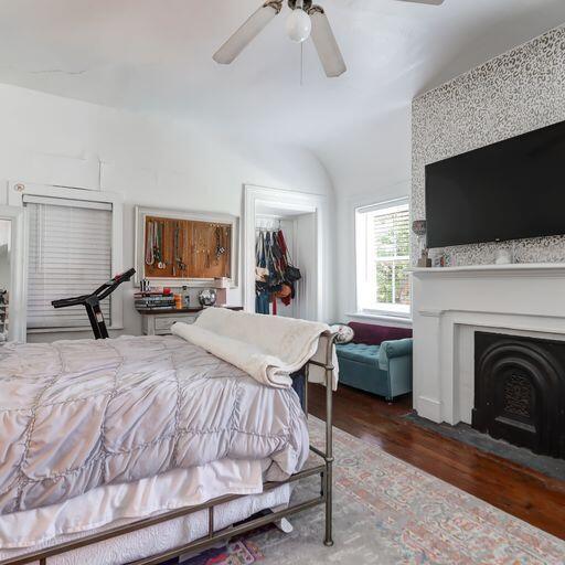 81 Rutledge Ave, Charleston, SC 29401 - bedroom featuring wood finished floors, a closet, a fireplace with flush hearth, ceiling fan, and a walk in closet