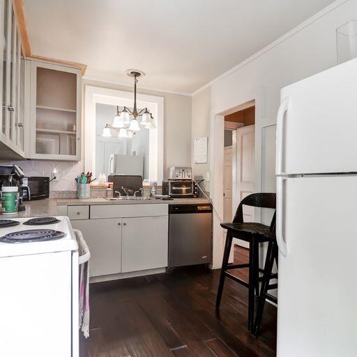 81 Rutledge Ave, Charleston, SC 29401 - kitchen featuring white appliances, a chandelier, dark wood-style flooring, light countertops, and ornamental molding