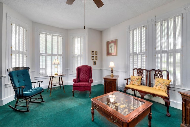 living area featuring carpet, a textured ceiling, and ceiling fan