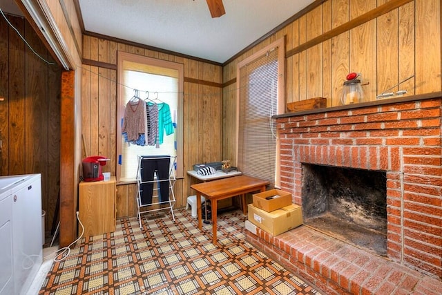 living room with wood walls, a fireplace, ceiling fan, and ornamental molding