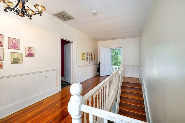 staircase featuring wood-type flooring and an inviting chandelier