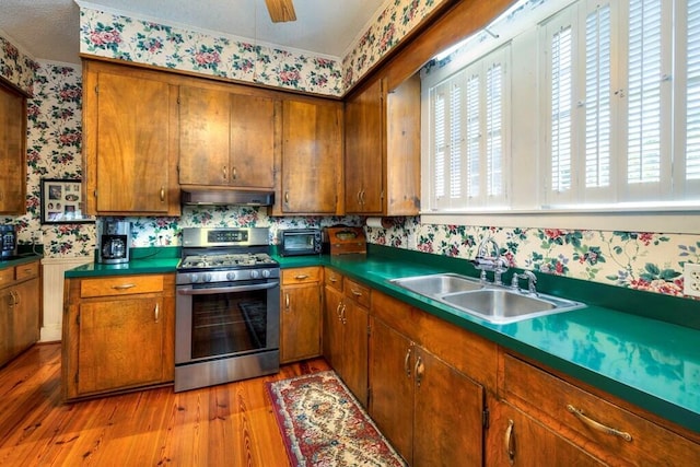 kitchen featuring sink, stainless steel gas range, light hardwood / wood-style flooring, plenty of natural light, and exhaust hood