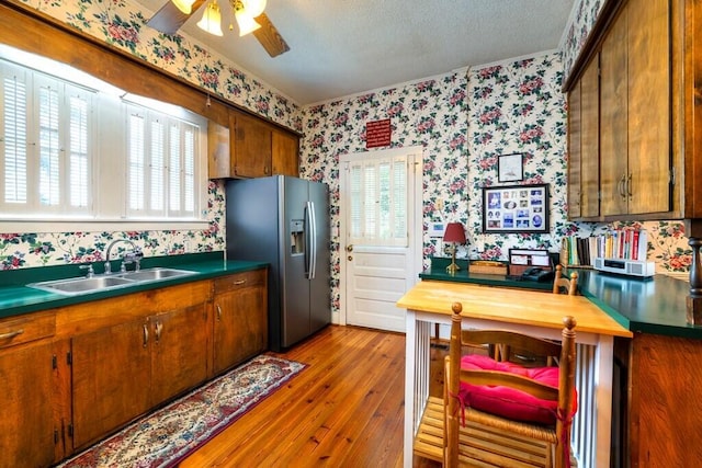 kitchen featuring a wealth of natural light, sink, stainless steel fridge with ice dispenser, a textured ceiling, and light wood-type flooring