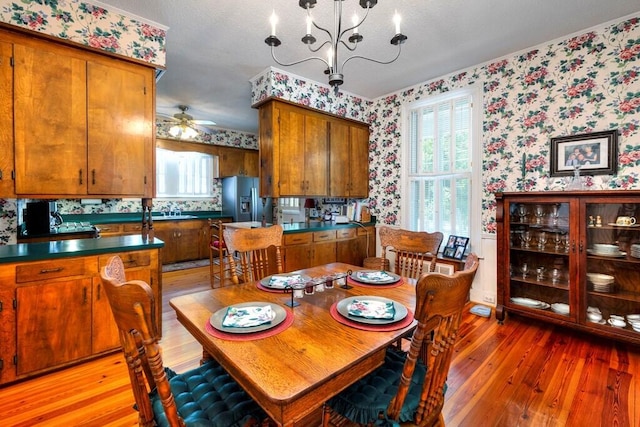 dining area with ceiling fan with notable chandelier and light hardwood / wood-style flooring