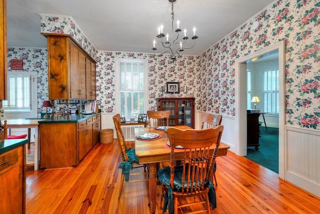 dining space featuring crown molding, light hardwood / wood-style flooring, and a notable chandelier