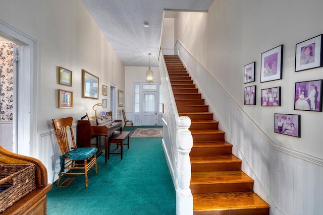 stairs featuring carpet flooring, a towering ceiling, and a textured ceiling