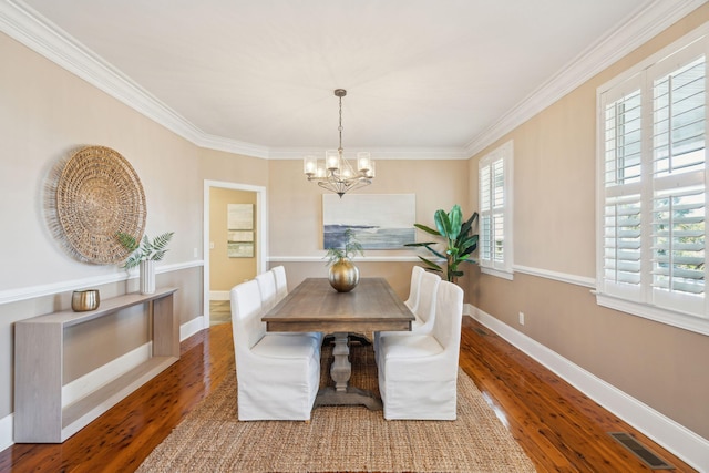 dining room with hardwood / wood-style flooring, visible vents, baseboards, ornamental molding, and an inviting chandelier