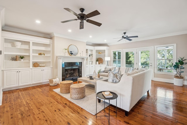 living area featuring crown molding, a fireplace, recessed lighting, wood-type flooring, and baseboards