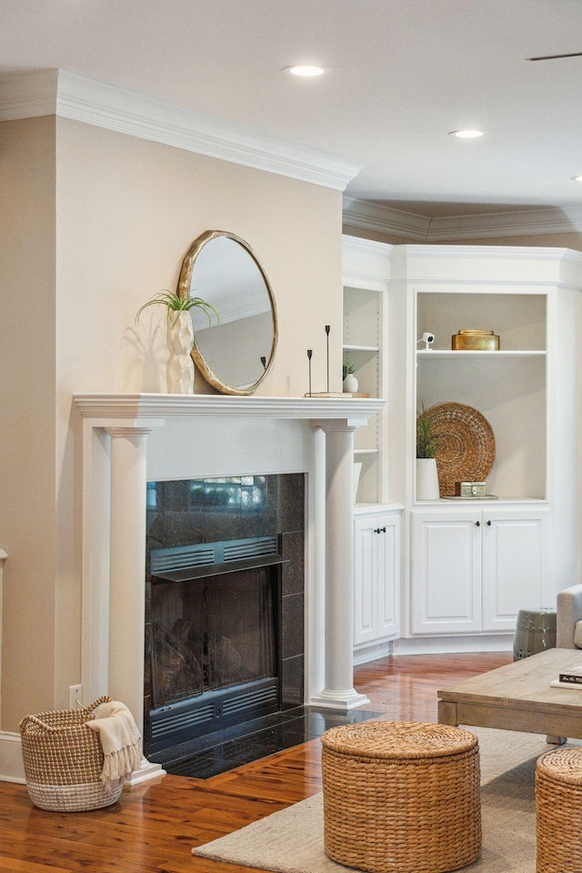 living area with crown molding, built in shelves, wood finished floors, and recessed lighting