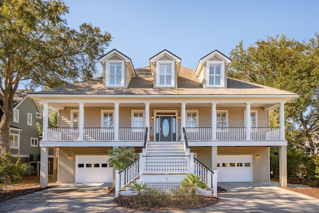 raised beach house featuring an attached garage, a porch, concrete driveway, and stucco siding