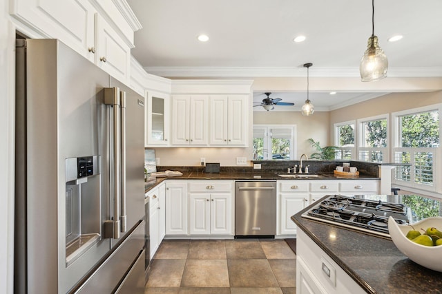 kitchen featuring a peninsula, stainless steel appliances, crown molding, white cabinetry, and a sink